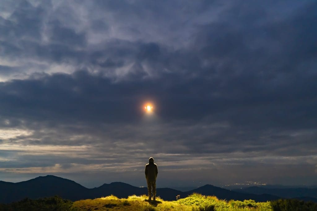 The UFO shines on a male standing on the mountain